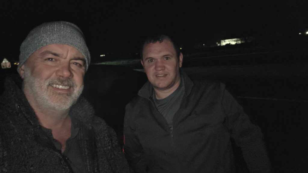 A selfie picture of Darron Mark and Eamon Kenney taken at night, after Eamon had helped with a puncture at the side of the road.