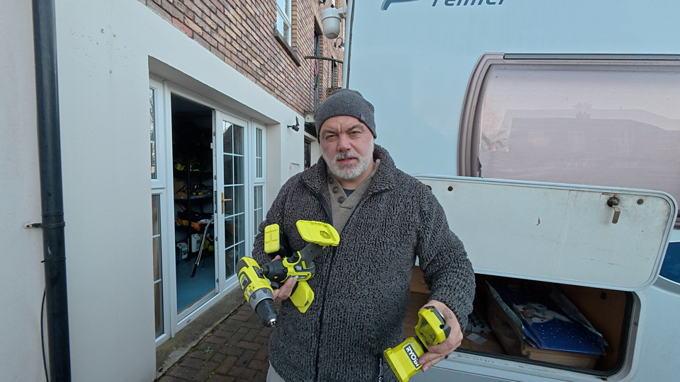 Darron is seen holding various Ryobi tools as he organises his motorhome's garage.